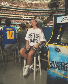 a woman sitting on top of a chair in front of a tv screen at a sporting event