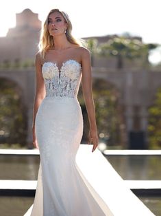 a woman in a white wedding dress is walking down the runway with her hand on her hip