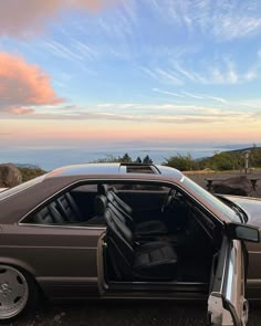 a car with its door open sitting on the side of a road next to some rocks