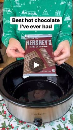 a person holding a box of hershey's chocolate in front of a slow cooker