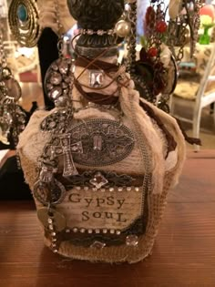 an old bottle is sitting on a table with many other items around it and some glass beads hanging from the top