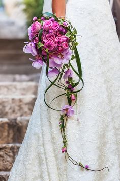 a bride holding a bouquet of purple flowers