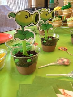 a table topped with cupcakes covered in green frosted icing and plants