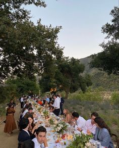 a group of people sitting at a long table with food and drinks in front of them