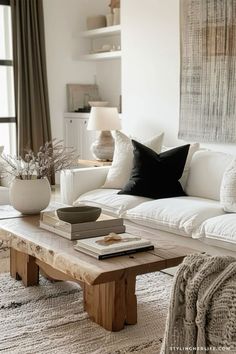 a living room filled with white furniture and pillows on top of a wooden table in front of a window