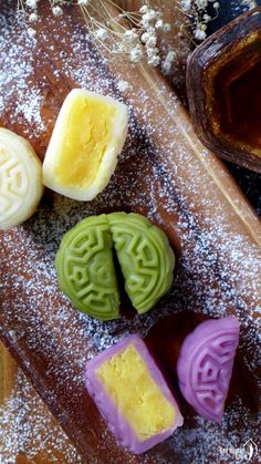 four different types of soaps on a wooden cutting board with powdered sugar and honey in the background