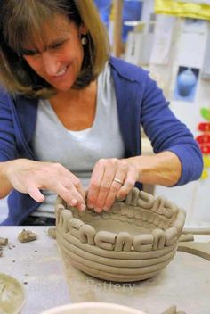 a woman is making a vase out of clay