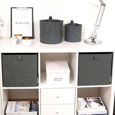 a white book shelf with three bins and two baskets on top, next to a lamp