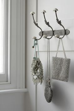 three hooks are hanging on the wall with purses