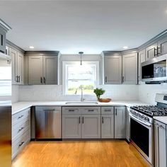 an empty kitchen with stainless steel appliances and wood flooring is pictured in this image