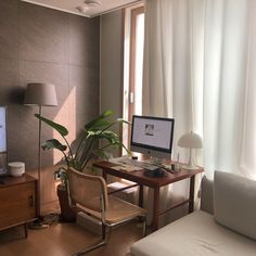 a living room with a couch, chair and computer monitor on the desk in front of a window