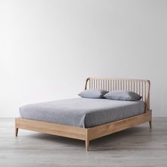 a bed with two pillows on top of it and a wooden frame in the middle