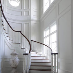 an elegant staircase with white walls and railings leading up to the second floor window