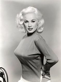 an old photo of a woman with blonde hair wearing a dress and posing for the camera