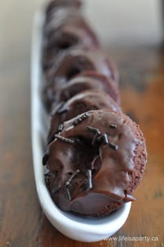 chocolate covered doughnuts in a white dish on a wooden table