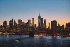 the city skyline is lit up at night as seen from across the river in new york