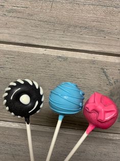 three colorful lollipops sitting on top of each other in front of a wooden surface