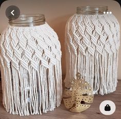 two mason jars decorated with white crocheted yarn and metal lids, one has a gold fish on it