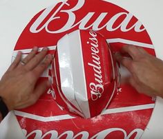 two hands are holding up a large red and white round box with the word bud's on it