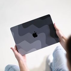 a person holding an apple laptop in their hands