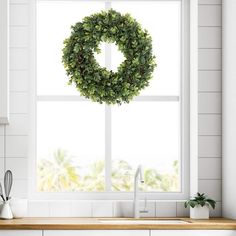 a kitchen window with a wreath hanging over it