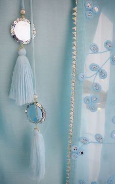 two tassels hanging from the side of a curtain with beads and pearls on it