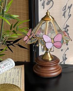 a lamp that is on top of a table next to a potted bamboo plant