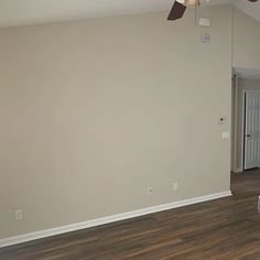 an empty living room with hard wood floors and ceiling fan in the middle of the room