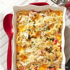 a casserole dish with chicken, cheese and vegetables in it next to a red spoon