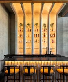 a bar with yellow chairs and bottles on the wall