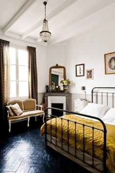 a bed room with a neatly made bed next to a chair and a mirror on the wall