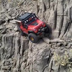 a red jeep driving up a rocky hill