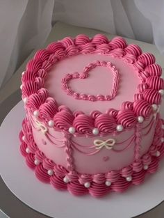 a heart shaped cake with pink icing and white decorations