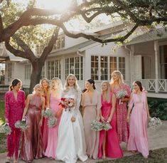 a group of women standing next to each other in front of a house with trees