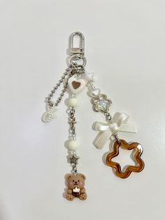 a keychain with two charms attached to it's sides and a teddy bear on the other side