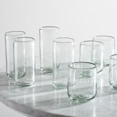 several clear glass vases lined up on a marble counter top with the words west elm written below them