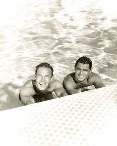 two men are in the water on their stomachs and one man is smiling at the camera