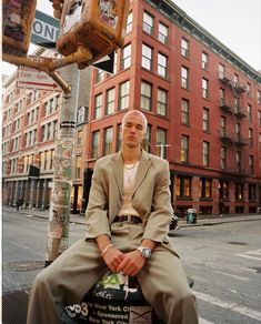 a man sitting on top of a pole next to a traffic light in the city