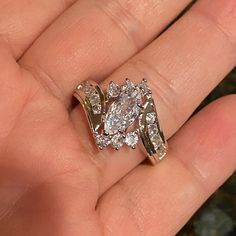 a close up of a person's hand holding an engagement ring with two rows of diamonds