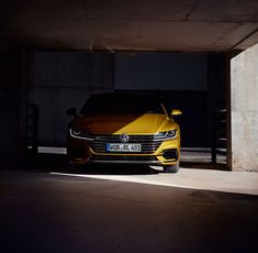 the front end of a yellow car parked in a parking garage with its lights on