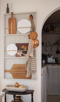 a kitchen with white walls and wooden utensils hanging on the wall above it