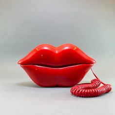 a red telephone sitting on top of a table next to a large lips mouth shaped object