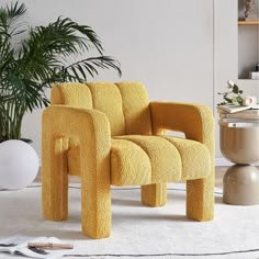 a yellow chair sitting on top of a white rug next to a potted plant