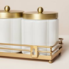 two salt and pepper shakers sitting on top of a metal tray with gold handles