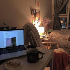 an open laptop computer sitting on top of a white desk next to a cup and saucer