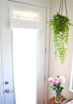 a room with a door and some flowers in a vase on the side table next to it