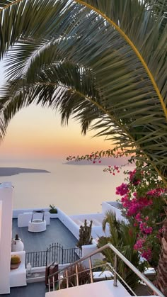 the sun is setting over the water and palm trees in front of some white buildings