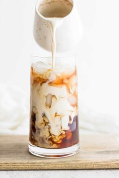 someone pouring coffee into a glass with ice