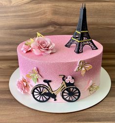 a pink cake decorated with flowers and the eiffel tower in paris, france