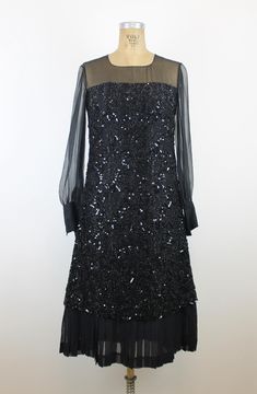 1970s Vintage Black Sequin Dress with Sheer Sleeves Embrace the captivating charm of the 1970s with this dazzling vintage black sequin dress. The fully sequined body adds instant glamour, while the sheer chiffon sleeves bring a graceful and ethereal touch. The mix of textures creates a striking contrast that's both bold and elegant, making this dress perfect for special occasions or a night out. - Semi-sheer long sleeves with cuffed wrists - A-line silhouette with sequin detailing throughout - P Chiffon Sleeves, Dress 70s, Dress Silk, Black Sequin Dress, Sheer Chiffon, Sheer Sleeves, Silk Chiffon, Black Sequins, Dress Clothes For Women